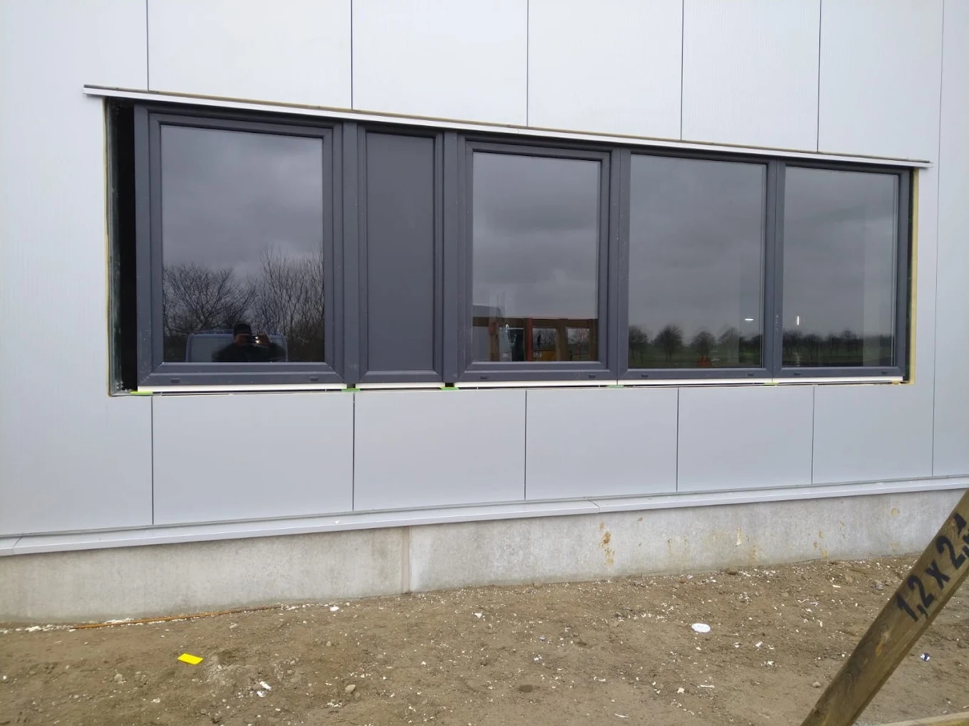 Rząd pięciu okien aluminiowych montowanych na elewacji budynku